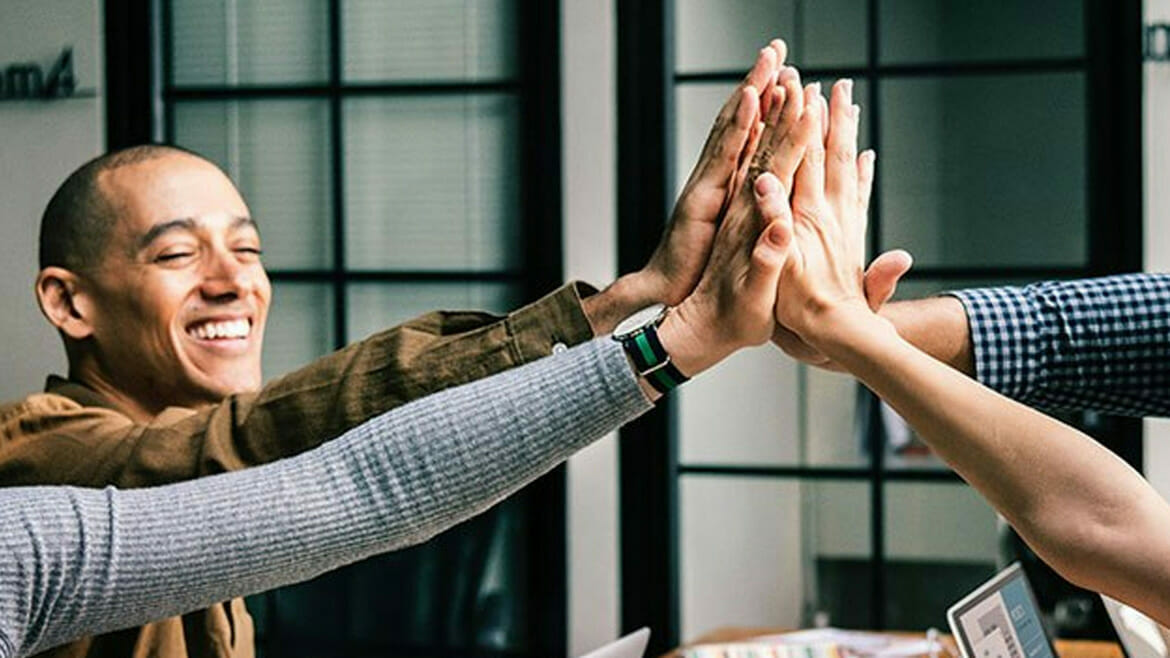 Flu-Proof Office: Four arms bumping elbows in a professional setting.