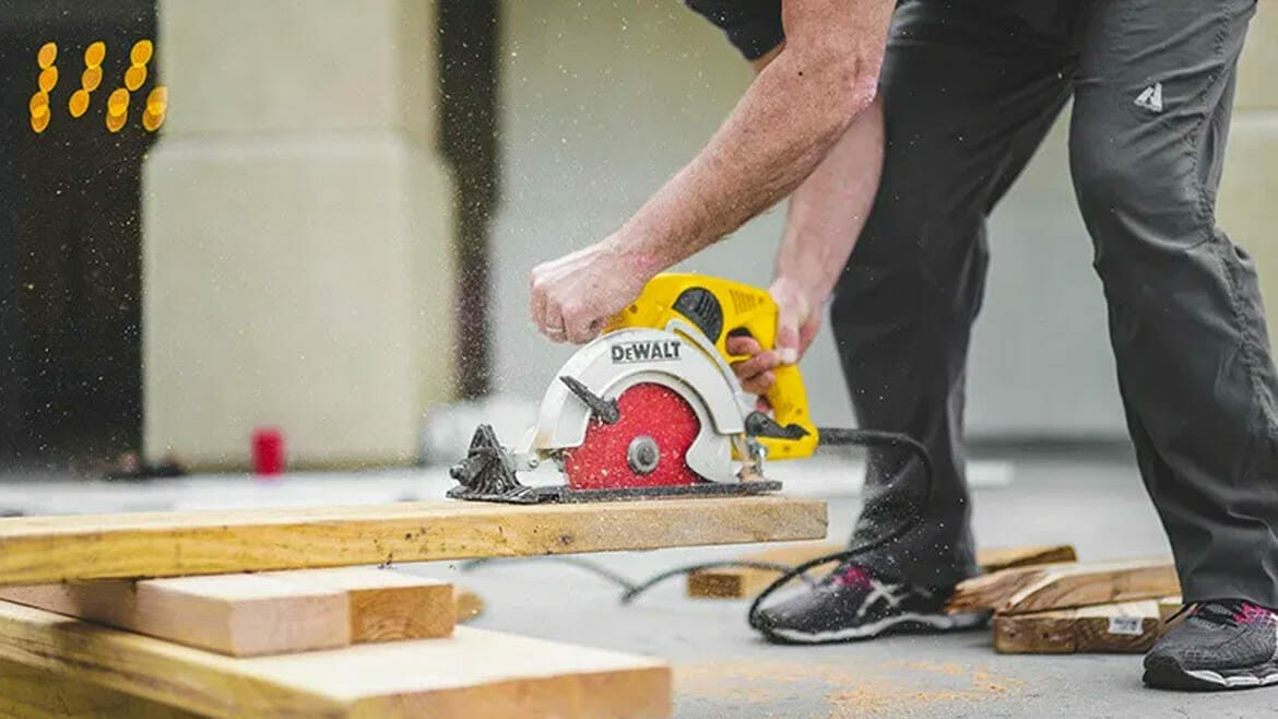 Construction Cleanup Services: Worker Cutting Wood with Saw