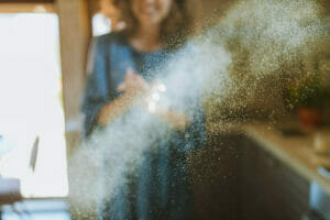 Woman sneezing due to allergies with visible dust particles in sunlight.