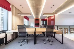 Open concept office space with four work chairs and a living room area with a television in the background.