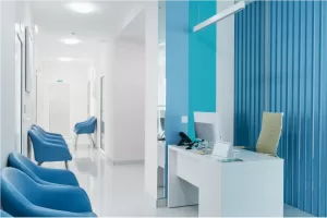 Modern office hallway with blue chairs and reception desk displaying a clean and organized workspace.